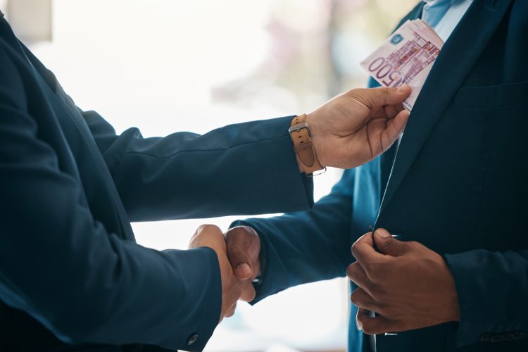 Handshake, money and bribery deal between businessmen in partnership in a corporate company office